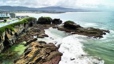 Nefes kesen bir hava perspektifi engebeli kayalık kıyı şeridi mavi dalgalar ve cennet gibi bir plaj.