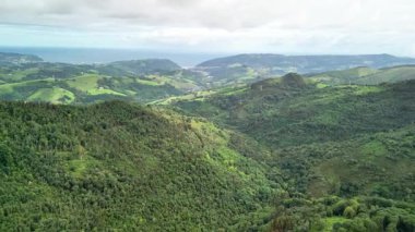 Parlak okyanusla birleşen yemyeşil tepelerin çarpıcı hava manzarasını tecrübe edin.