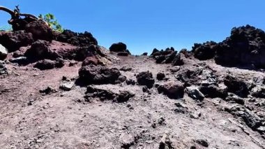 Açık mavi gökyüzünün altındaki kayalık araziyle süslenmiş bu nefes kesici volkanik araziyi keşfetmek için bir dakikanızı ayırın.