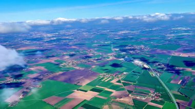 Göz kamaştırıcı bir hava manzarası. Parlak mavi gökyüzüne karşı canlı ekinler ve kabarık bulutlar sergiliyor.