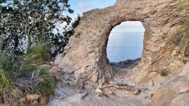 Huzurlu ve sakin bir sahil manzarası. Huzurlu sulara bakan heybetli kayalık bir kemer yolu.