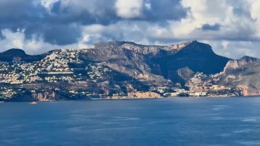 Dağılmış bulutlarla dolu güzel bir gökyüzünün altında nefes kesici kıyı dağları manzarası.