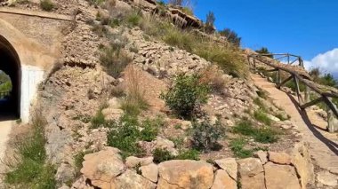 Resmedilmeye değer taş bir patika kıyı yamacı boyunca esiyor, yeşillik ve nefes kesici deniz manzaraları sergiliyor.