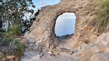 Huzurlu ve sakin bir sahil manzarası. Huzurlu sulara bakan heybetli kayalık bir kemer yolu.