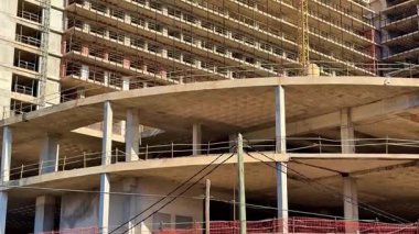 Dinamik ve etkileyici bir inşaat alanı açık mavi gökyüzünün altında birden fazla vinç ve iskelet sergiliyor.