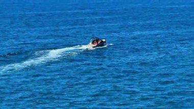 Zarif bir motorlu tekne, ışıldayan mavi sularda zarafetle süzülür, ardında nazikçe bir uyanış bırakır.