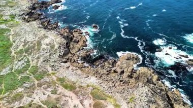 Şaşırtıcı derecede canlı bir sahil şeridi boyunca kayalara çarpan hava dalgalarını keşfedin.