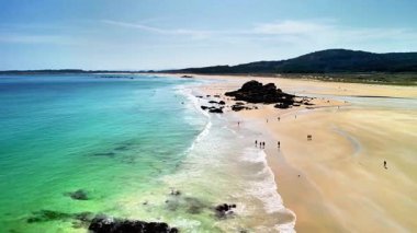 Bu, kristal berrak suları, güzel altın kumları ve eşsiz kayalık oluşumları gösteren çarpıcı bir plaj sahnesi.