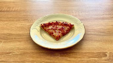 Çok cazip ve lezzetli bir dilim pepperonili pizza, büyüleyici bir klasik tabakta sunuluyor.