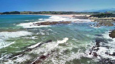 Dalgaların kayalık kıyılara çarptığı sakin bir kıyı şeridinin nefes kesici ve görkemli manzarasını deneyimleyin.