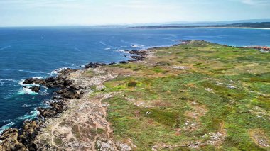 Göz kamaştırıcı bir kıyı manzarası, kayalık kıyı şeritleri ve canlı, gür yeşillikler sunar.
