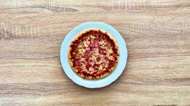 Lezzetli, ağız sulandıran, ahşap bir masa üzerinde çeşitli malzemeler içeren bir pizza.