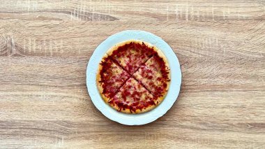 Tahta bir masada ustalıkla hazırlanmış peynir ve çeşitli aromalı malzemelerle süslenmiş baştan çıkarıcı bir pizza.