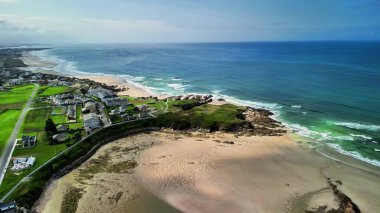 Sersemletici hava manzarası, kıyı şeridinin yanındaki canlı yeşil alanlarla huzurlu kıyı güzelliğini yakalıyor..