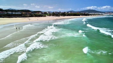 Nefes kesici bir sahil sahnesi, muhteşem turkuaz dalgaların sahilin altın kumlarına çarptığını gösteriyor.