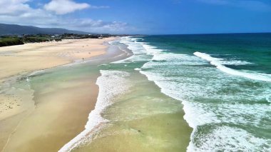 Güzel, sakin bir sahil. Nazikçe dalgaları kucaklayan ve berrak mavi bir gökyüzü. Rahatlamak ve gevşemek için ideal.