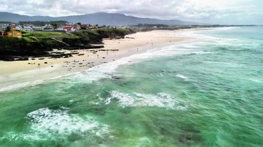 Bir hava görüntüsü, berrak suları ve canlı kıyı manzarası olan bir sahilin nefes kesici görüntüsünü yakalar. Bir cennet.