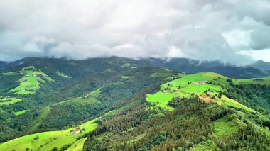 Dramatik bulutların altındaki canlı yeşil tepelerin ve vadilerin nefes kesici hava manzarasını tecrübe edin.