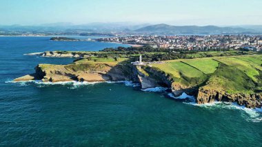 Havadan çekilen bir görüntüde büyüleyici kayalıklar ve deniz feneri, resim gibi kıyı manzaraları vurgulanıyor.