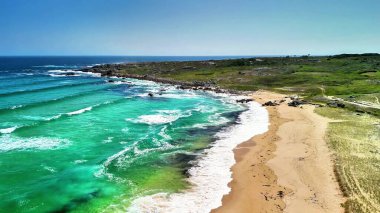 Muhteşem turkuaz suları ve canlı yeşilliği olan sakin bir plajın nefes kesici manzarasının tadını çıkar.