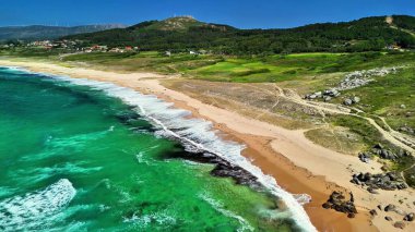 Kristal berrak suların ve yakınlardaki yemyeşil suların bulunduğu el değmemiş bir plajın nefes kesici hava manzarasına hayret ediyorum.