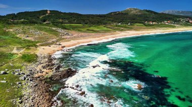Canlı turkuaz suları ve yemyeşil manzaraları olan el değmemiş bir plajın çarpıcı hava görüntüleri..