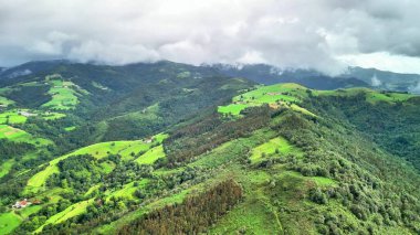 Nefes kesen bir hava görüntüsü gökyüzündeki dramatik bulut oluşumlarıyla birlikte canlı yeşil tepeler sergiliyor