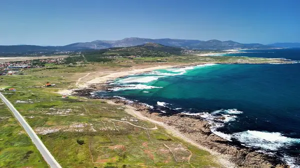 Sersemletici hava görüntüsü sakin bir sahil şeridini canlı yeşillikleri ve büyüleyici gök mavisi dalgaları yakalıyor.