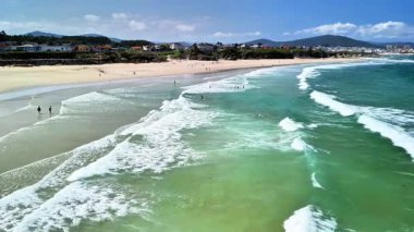 Nefes kesici bir sahil sahnesi, muhteşem turkuaz dalgaların sahilin altın kumlarına çarptığını gösteriyor.