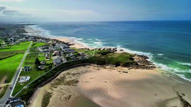 Sersemletici hava manzarası, kıyı şeridinin yanındaki canlı yeşil alanlarla huzurlu kıyı güzelliğini yakalıyor..