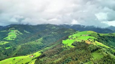 Dramatik bulutların altındaki canlı yeşil tepelerin ve vadilerin nefes kesici hava manzarasını tecrübe edin.