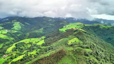 Nefes kesen bir hava görüntüsü gökyüzündeki dramatik bulut oluşumlarıyla birlikte canlı yeşil tepeler sergiliyor