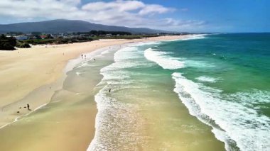 Muhteşem dalgalarla, yumuşak kumlarla ve mavi gökyüzünün altında huzurlu bir atmosferle baş döndürücü bir sahil manzarasının tadını çıkar.