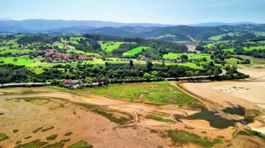 Yükselmiş bir manzara nehri akan yeşil bir manzarayı ve pitoresk tepeler arasındaki köprüyü gözler önüne seriyor.