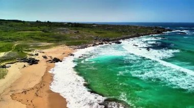 Sersemletici hava manzaraları sakin bir kıyı şeridini gösteriyor, canlı turkuaz suları vurguluyor ve yeşeren yeşillikler