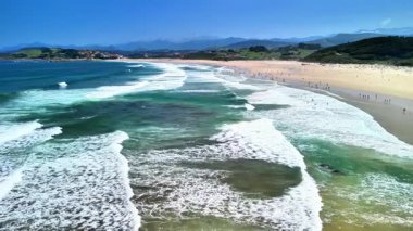 Nefes kesen bir sahil manzarası büyüleyici turkuaz dalgalar ve yumuşak kumlu sahilleri barındırır, hepsi berrak, mavi bir gökyüzünün altında.