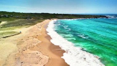 Yumuşak, ılık kumları, berrak gökyüzünün altında canlı mavi suların yanında gösteren nefes kesici bir kumsal sahnesi.
