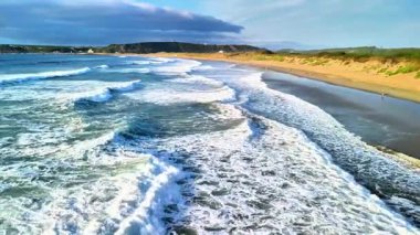 Okyanus dalgalarının çarpıcı güzelliğini deneyimleyin. Huzurlu, sakin bir plaja çarpan berrak mavi gökyüzünün altında.