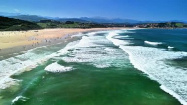 Güneşli bir plajın huzurlu güzelliğinin tadını çıkarın. Yumuşak dalgalar ve mutlu kumsalcılar zamanlarını en iyi şekilde değerlendiriyor.