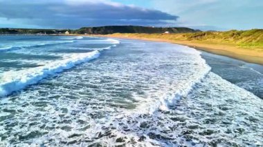 Muhteşem bir günbatımında kıyıya vuran dalgaların büyüleyici görüntüsü doğa meraklıları için mükemmel.