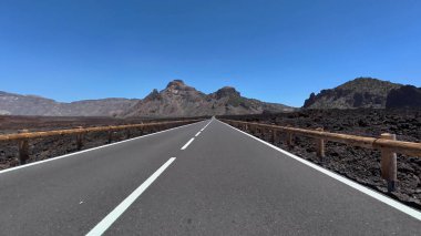 Çarpıcı bir manzara engebeli volkanik arazide ve görkemli uzak dağlarda dolambaçlı bir yola sahiptir.