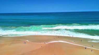 Büyüleyici turkuaz sularla, dalgalarla ve sıcak güneşin altında güneşlenen güneşlenenlerle büyüleyici bir sahneydi.