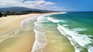 Muhteşem dalgalarla, yumuşak kumlarla ve mavi gökyüzünün altında huzurlu bir atmosferle baş döndürücü bir sahil manzarasının tadını çıkar.