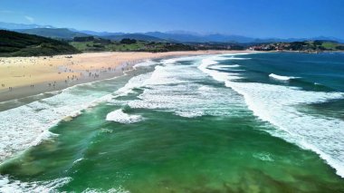 Güneşli bir plajın huzurlu güzelliğinin tadını çıkarın. Yumuşak dalgalar ve mutlu kumsalcılar zamanlarını en iyi şekilde değerlendiriyor.