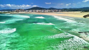 Canlı yeşil okyanus dalgaları, el değmemiş kumlu plajlar ve parlak mavi gökyüzü manzarasının tadını çıkar.