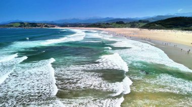 Nefes kesen bir sahil manzarası büyüleyici turkuaz dalgalar ve yumuşak kumlu sahilleri barındırır, hepsi berrak, mavi bir gökyüzünün altında.