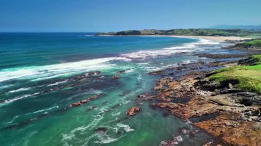 Temiz su, engebeli kayalar ve güneşli gökyüzünün altındaki yeşil tepeler ile güzel bir sahil manzarası, dinlenmek için ideal.