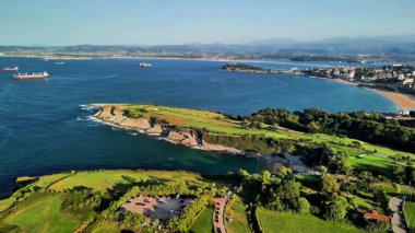 Çarpıcı şehir manzaralı ve çevresini çevreleyen canlı, yemyeşil bir kıyı manzarası.