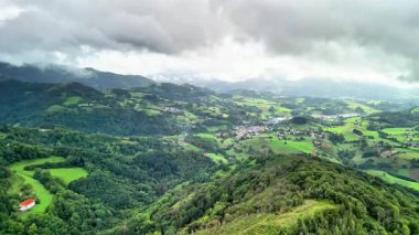 Yuvarlanan tepelerin nefes kesici kuş bakışı manzarası ve güzel, bulutlu bir gökyüzüne karşı kurulmuş canlı yeşillik.