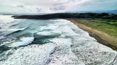 Güzel bir sahil manzarasında sakin bir plaja çarpan dalgaların gerçekten çarpıcı manzarasının tadını çıkarın.